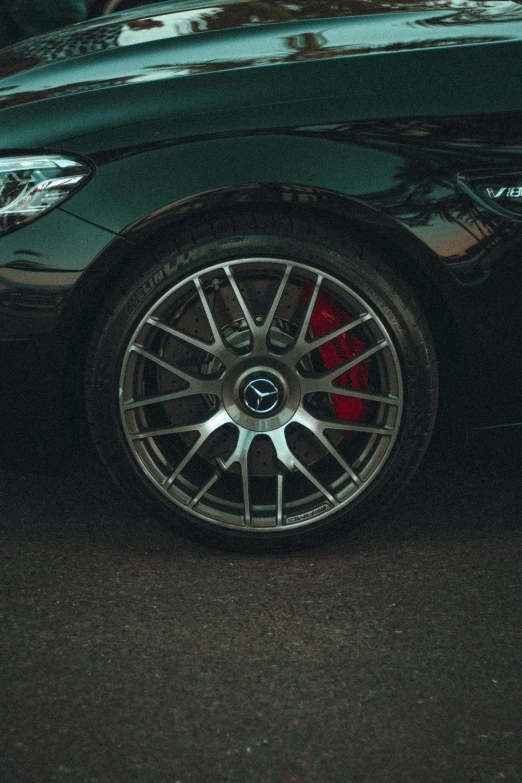 a black car parked on the side of the road, detailed alloy wheels, colour photograph, small, ad image