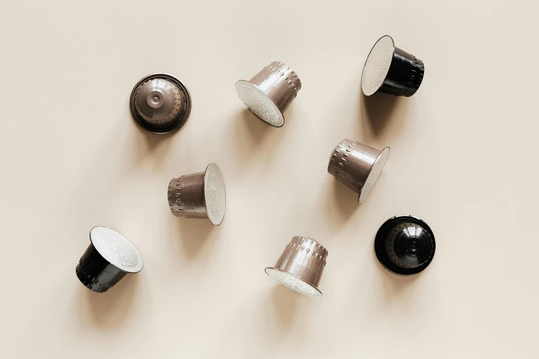 a group of coffee cups sitting on top of a table, inspired by Perin del Vaga, plasticien, metallic buttons, pod, product photo, on a pale background