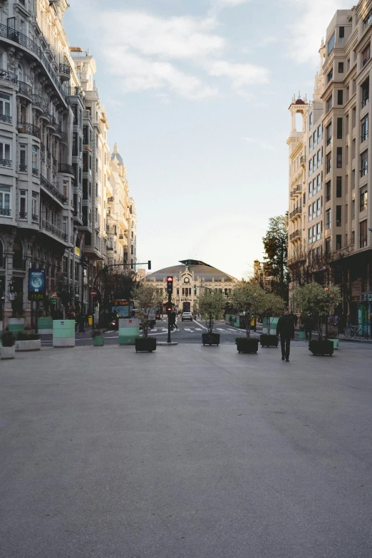 a man riding a skateboard down a street next to tall buildings, a picture, by Pablo Rey, unsplash, on a great neoclassical square, madrid, sparsely populated, lots of shops