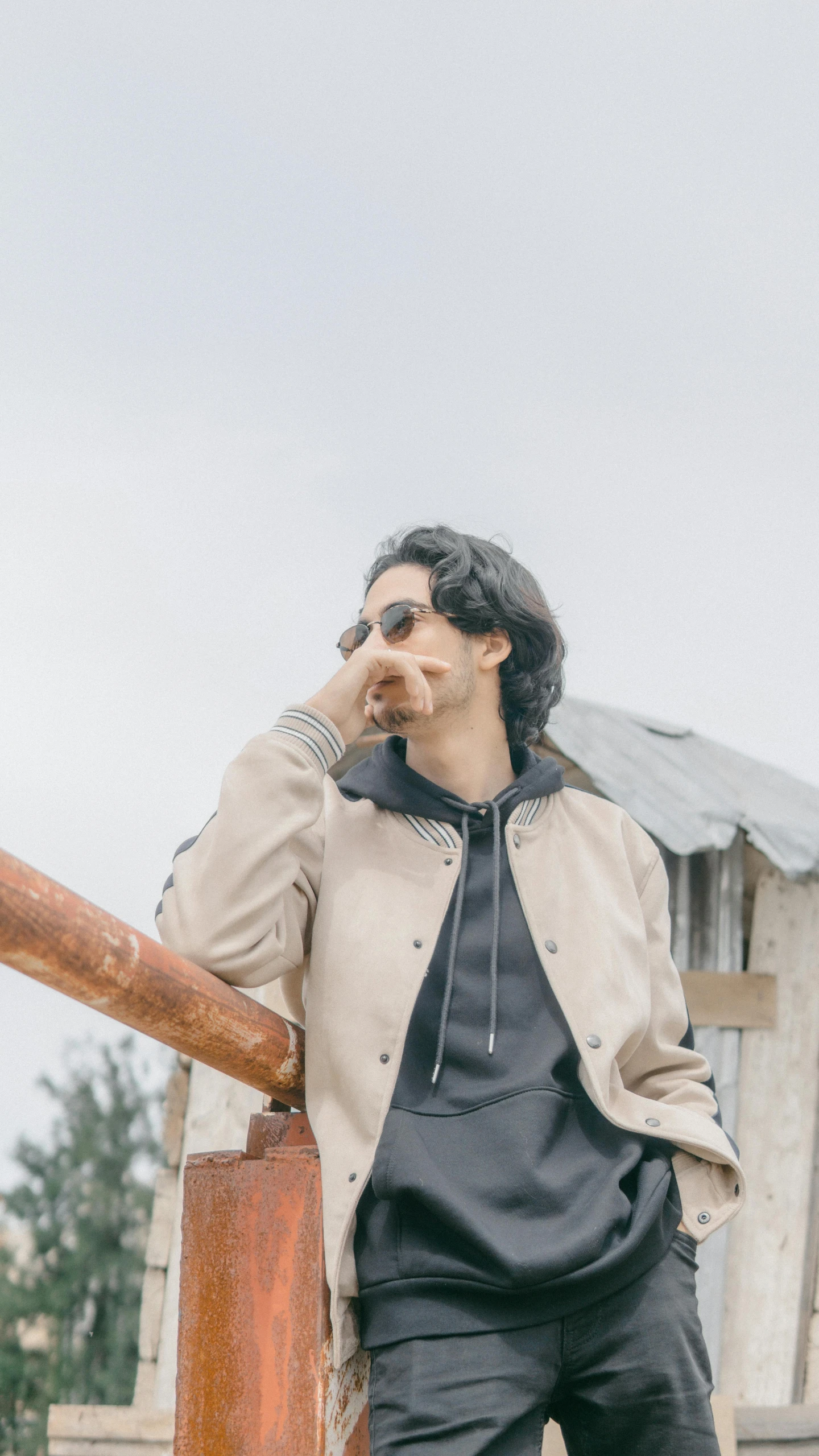 a man leaning on a railing talking on a cell phone, an album cover, trending on pexels, photorealism, beige hoodie, shot in the sky, 15081959 21121991 01012000 4k, alejandro