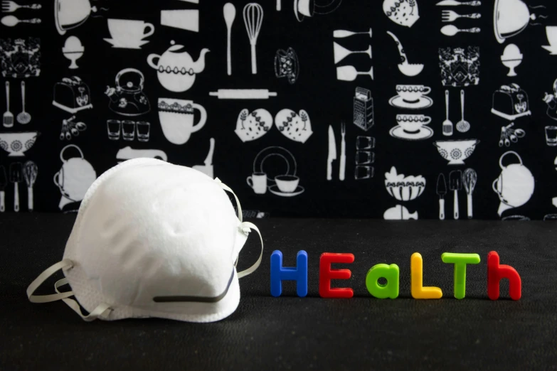 a white face mask sitting on top of a table, by Elaine Hamilton, pixabay, colorful medical equipment, chef hat, text morphing into objects, toys