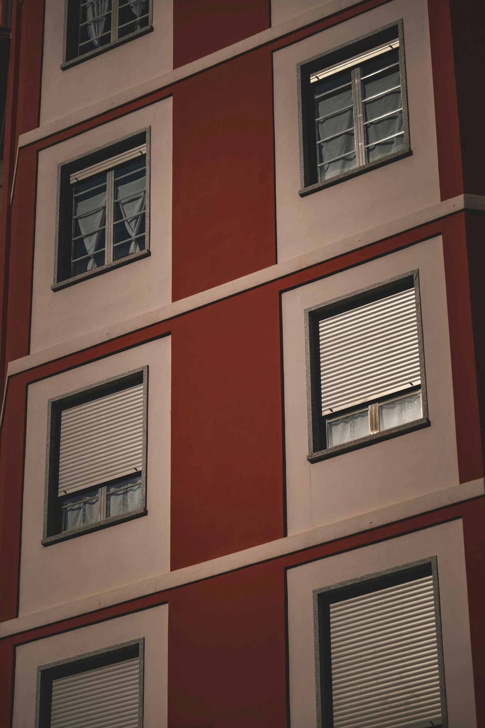 a tall red and white building with lots of windows, inspired by Elsa Bleda, pexels contest winner, neighborhood outside window, metal shutter, brown, desaturated color