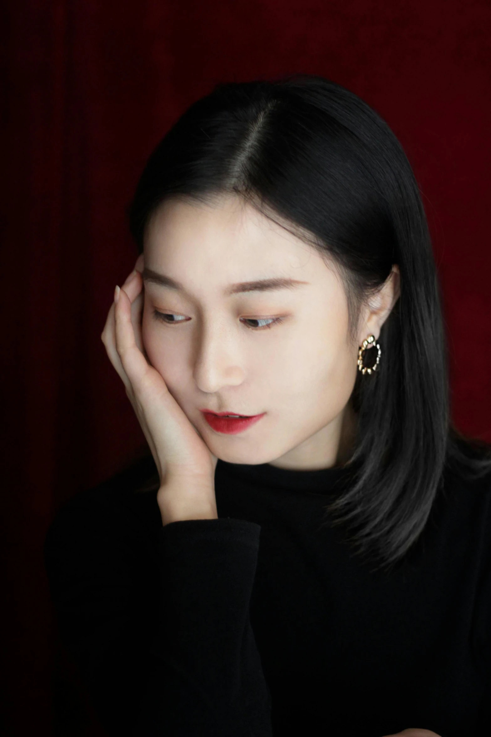 a woman sitting at a table with her hand on her face, a picture, inspired by Zhang Xuan, trending on pexels, silver earring, red velvet, headshot profile picture, deep black