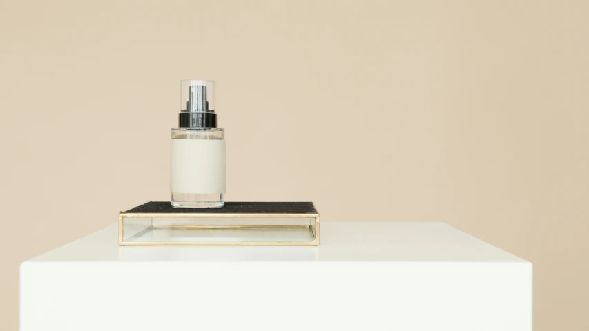 a bottle of perfume sitting on top of a white table, a minimalist painting, inspired by Agnes Martin, unsplash, dezeen, cream - colored room, evan lee, rectangle