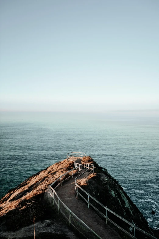 a lighthouse sitting on top of a cliff next to the ocean, looking down on the view, near a jetty, amanda lilleston, photo of the middle of the ocean