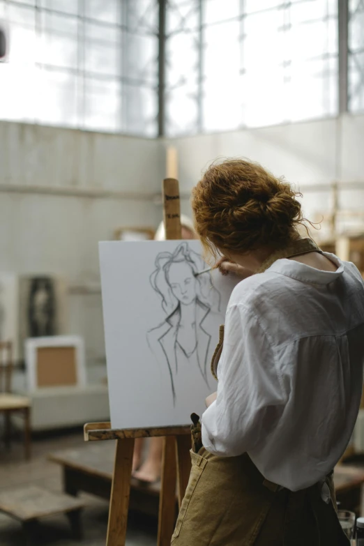 a woman standing next to a easel with a drawing on it, a charcoal drawing, trending on pexels, academic art, looking from shoulder, royal painting, center of image, looking across the shoulder