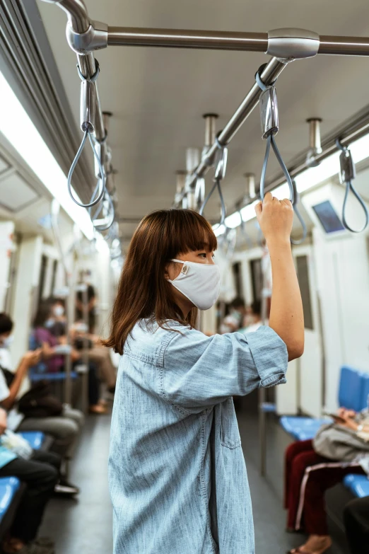 a woman wearing a face mask while riding a subway, happening, square, scientific photo, hanging, grey