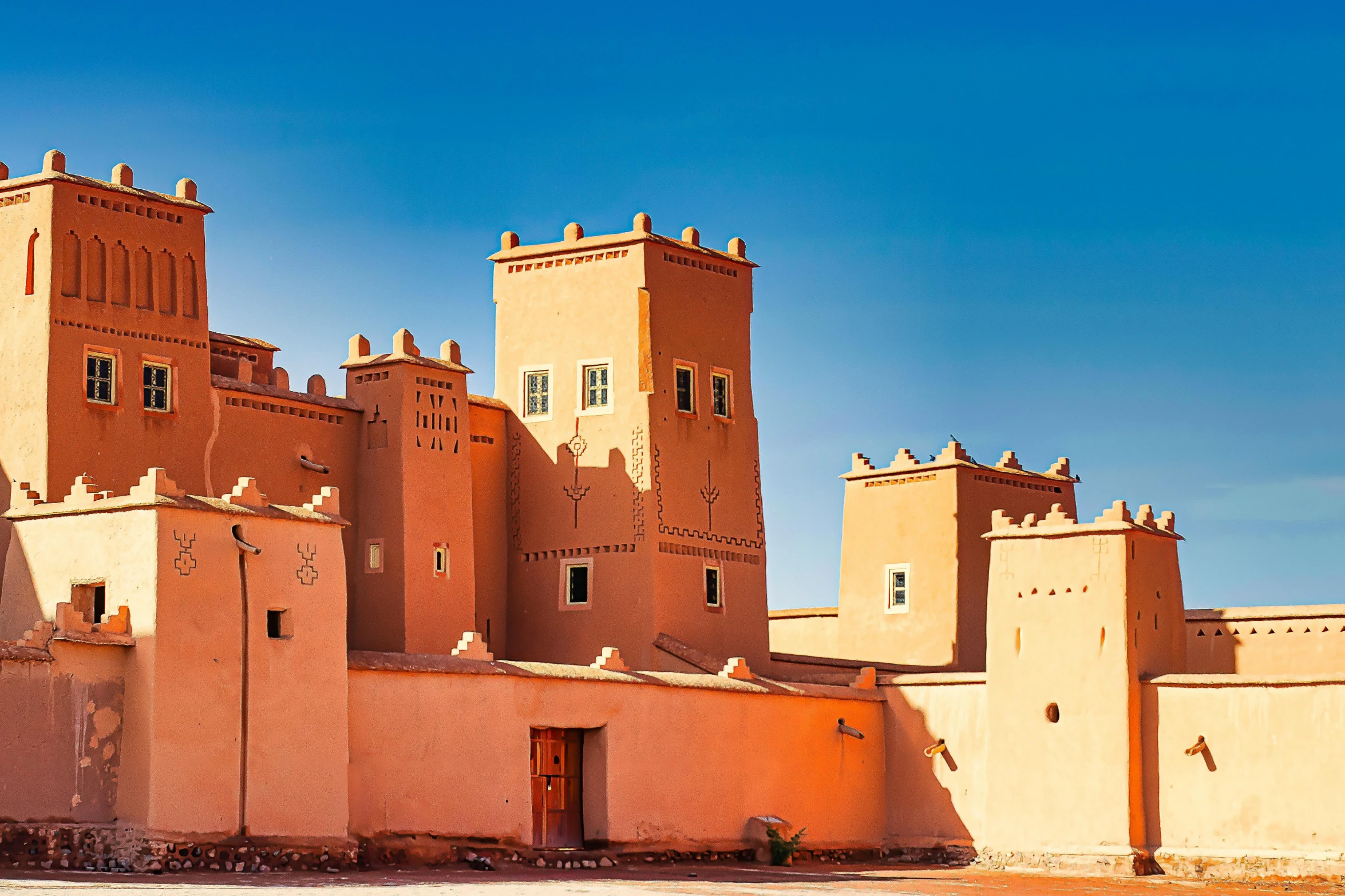 a large brown building sitting on top of a dirt field, inspired by Alberto Morrocco, pexels contest winner, les nabis, moorish architecture, red sand, pink, 1 4 9 3