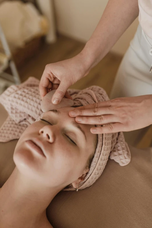 a woman getting a facial massage at a spa, by Adam Marczyński, trending on pexels, renaissance, square facial structure, light toned, head down, ilustration