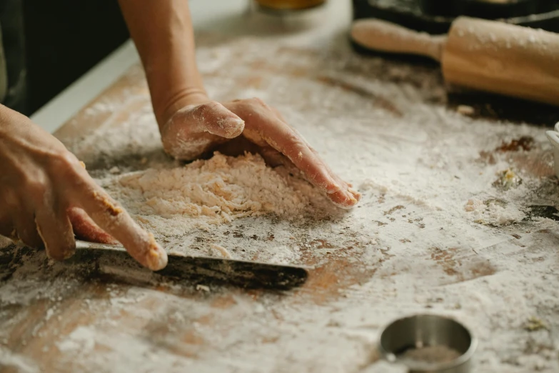 a close up of a person making food on a table, trending on pexels, flour dust, paw pads, background image, portrait photo