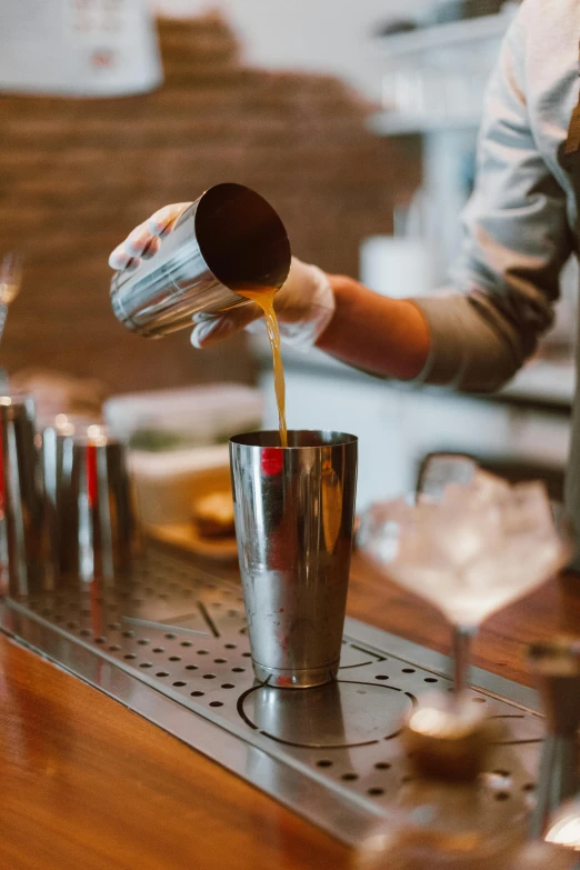 a bartender pours a drink at a bar, a digital rendering, unsplash, stainless steal, brown, vanilla, college