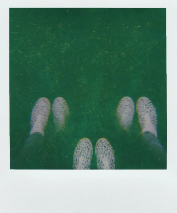 a person standing in the grass with their feet up, a polaroid photo, inspired by Ren Hang, unsplash, postminimalism, gelatinous symmetrical, dark green water, fluorescent spots, white shoes