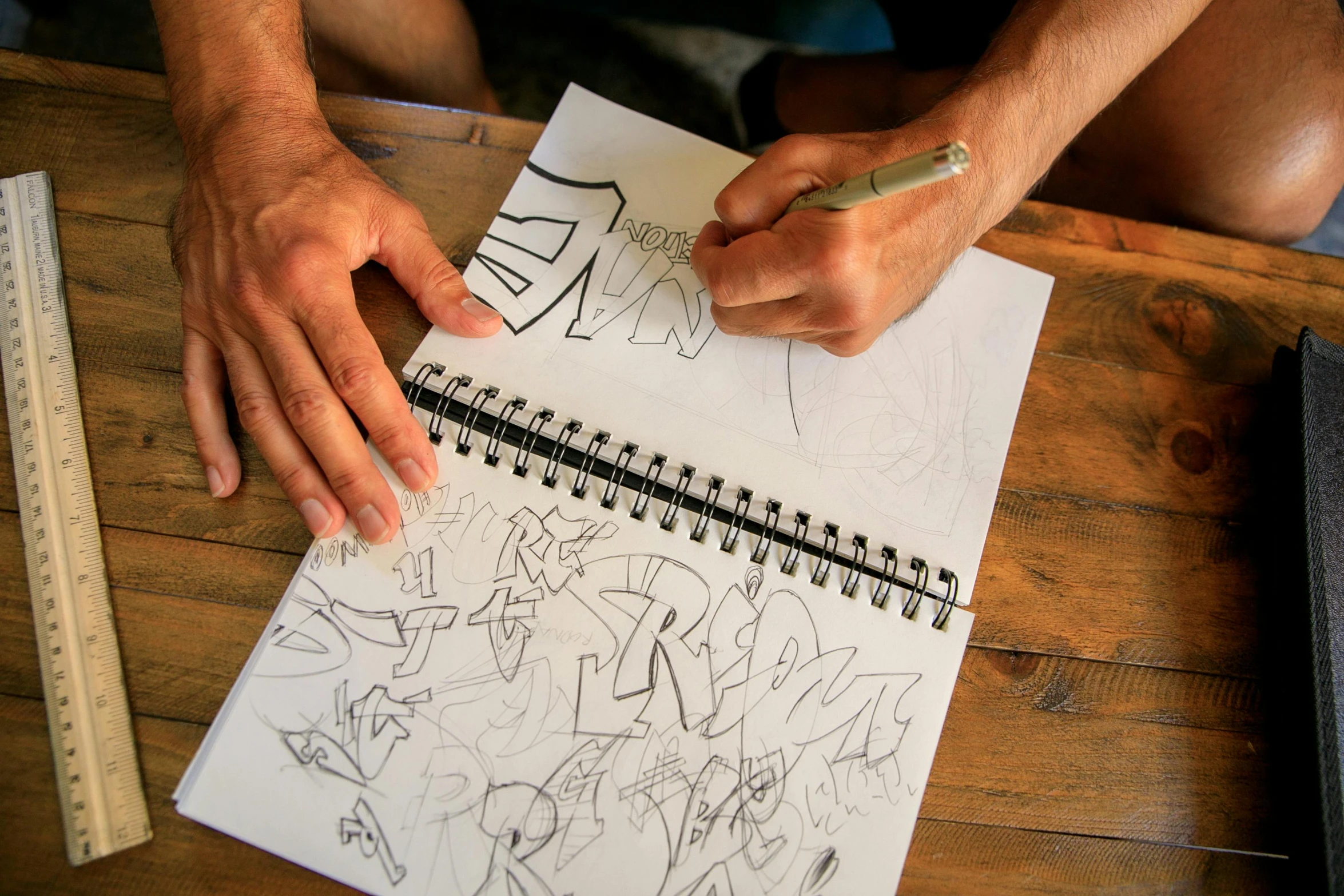 a man is drawing on a piece of paper, a sketch, by Jeremy Henderson, bubble letters, fan favorite, sketch book, promo image