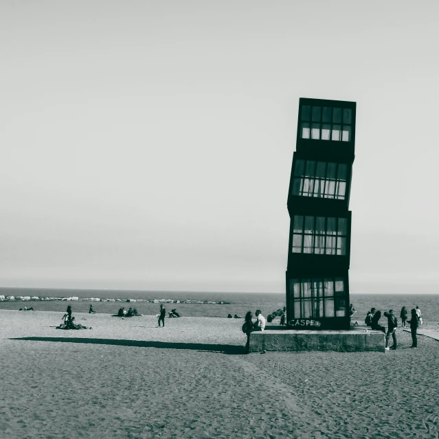 a tall tower sitting on top of a sandy beach, a black and white photo, unsplash contest winner, conceptual art, venice biennale, the cube, people in beach, in barcelona