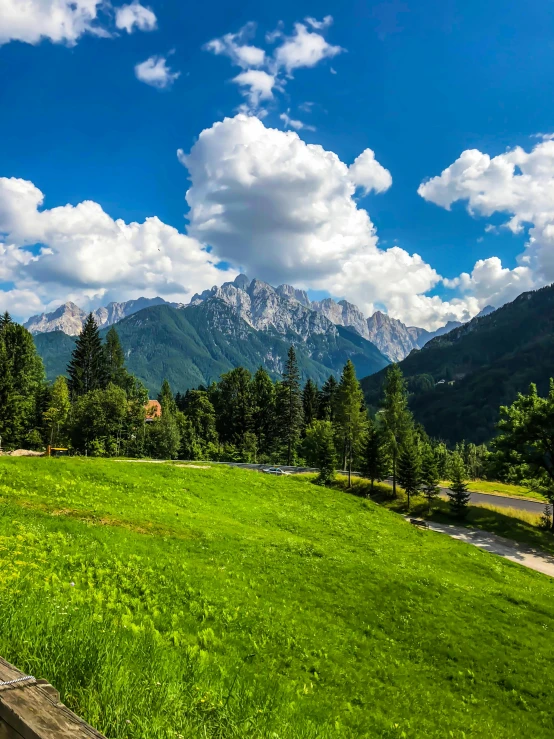 a wooden bench sitting on top of a lush green field, a picture, inspired by January Suchodolski, pexels contest winner, grand majestic mountains, square, slovenian, thumbnail