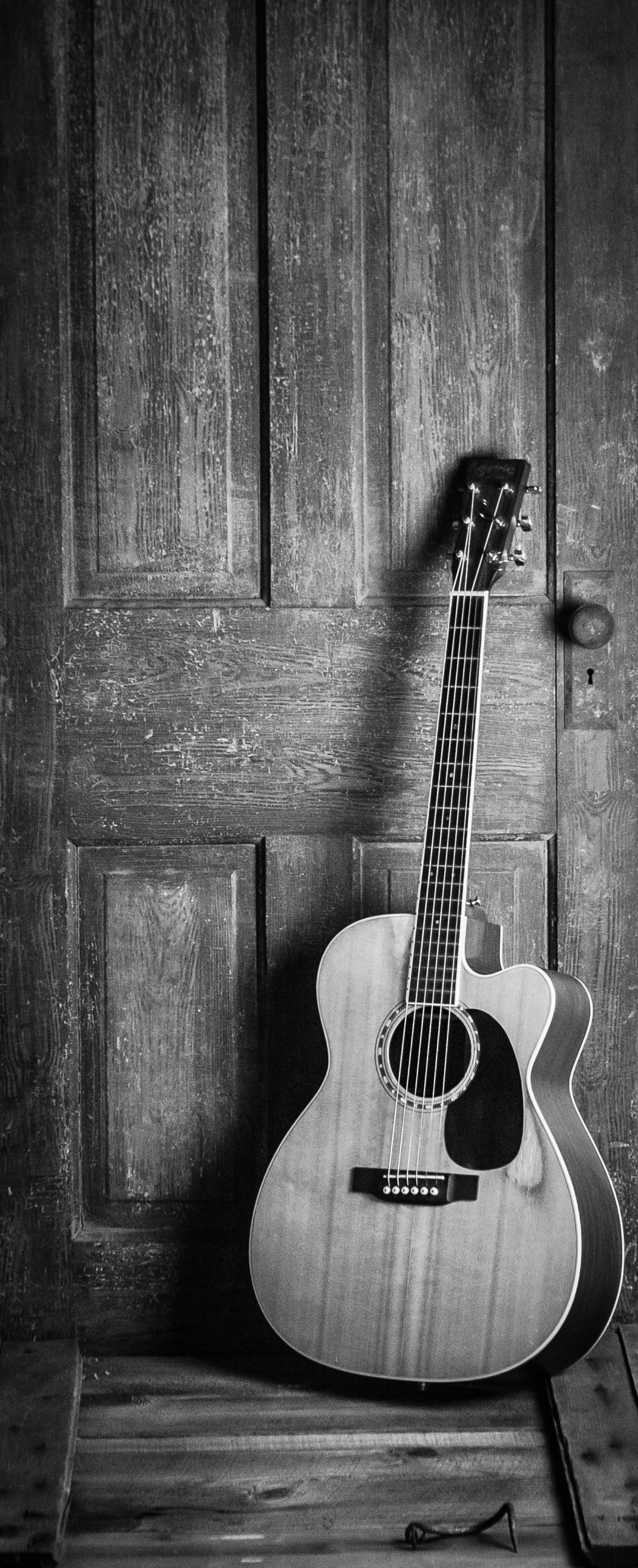 a black and white photo of an acoustic guitar, by Jim Manley, pexels contest winner, romanticism, a door you must never open, a wooden, dressed in a worn, fine