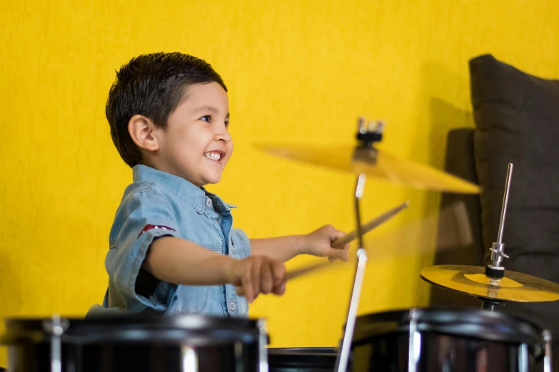 a young boy playing drums in a living room, pexels contest winner, yellow, avatar image, dynamic closeup, happy kid