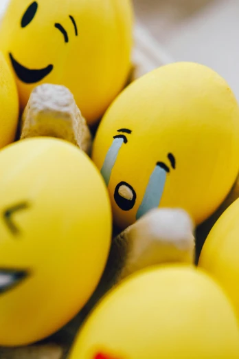 a bunch of yellow eggs with faces drawn on them, a cartoon, trending on pexels, happening, emoticon, drops, hugs, blurred
