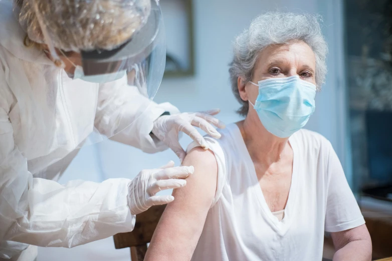 a woman getting a vaccine from a doctor, a portrait, by Adam Marczyński, shutterstock, haze over the shoulder shot, elderly woman, covered in bandages, manuka