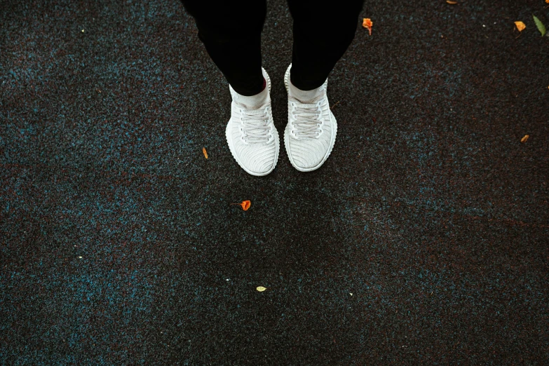 a person standing in the rain with an umbrella, wearing white sneakers, on a landing pad, looking from slightly below, chalk white skin