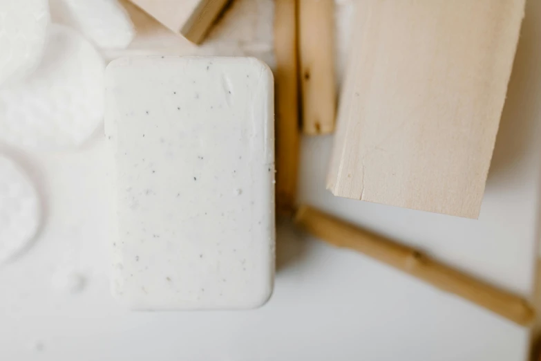 a couple of soap bars sitting on top of a counter, inspired by Rachel Whiteread, unsplash, white wood, background image, sustainable materials, covered in white flour