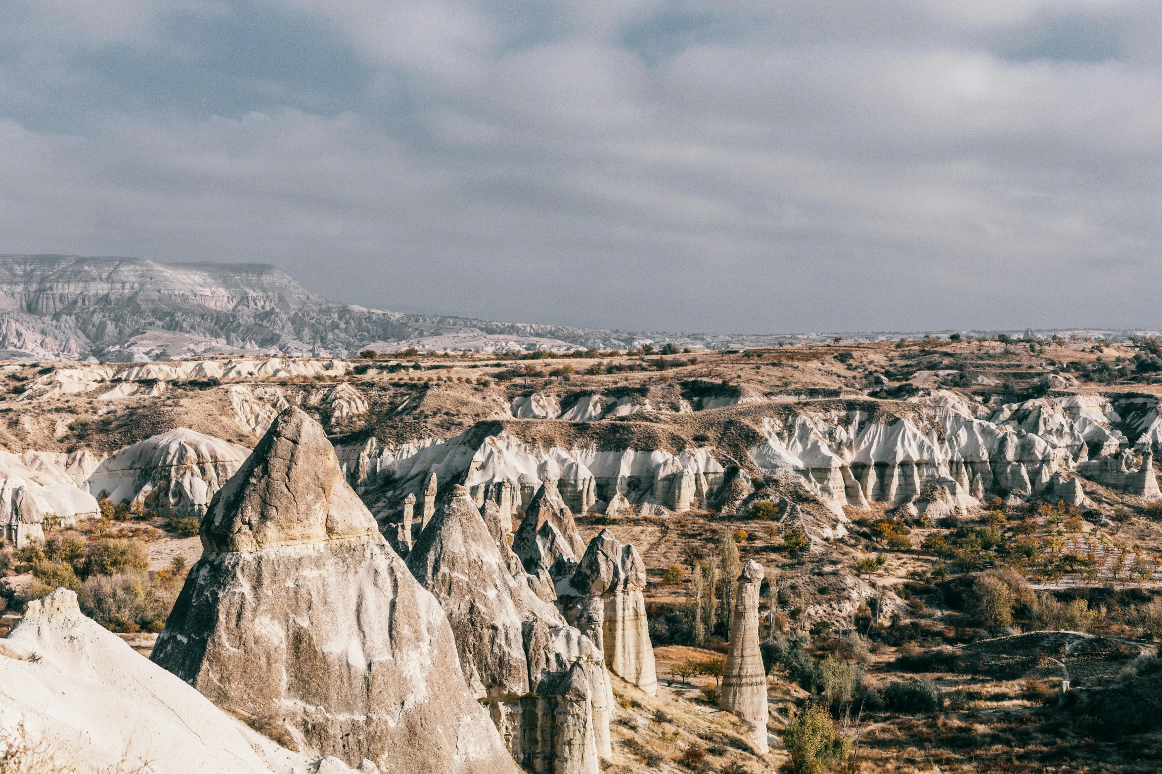 a person standing on top of a rock formation, pexels contest winner, art nouveau, black domes and spires, white travertine terraces, rolling foothills, geological strata