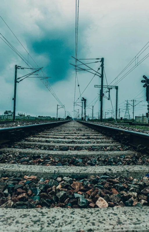 a train track with power lines in the background, an album cover, unsplash contest winner, vibrant but dreary blue, low quality photo, looking to the sky, platforms