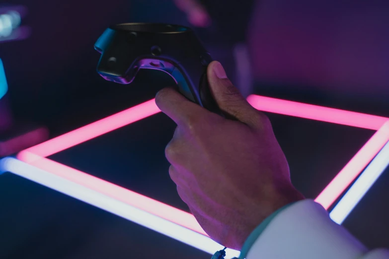 a close up of a person holding a video game controller, inspired by Beeple, interactive art, pink and blue lighting, inspect in inventory image, lazertag, phantom grip