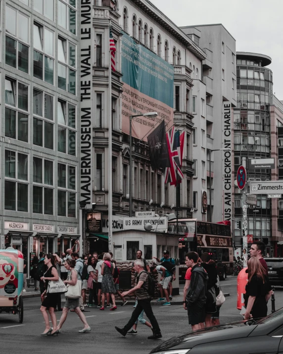 a group of people walking across a street next to tall buildings, pexels contest winner, viennese actionism, the british museum, lots of signs and shops, background image, lgbtq