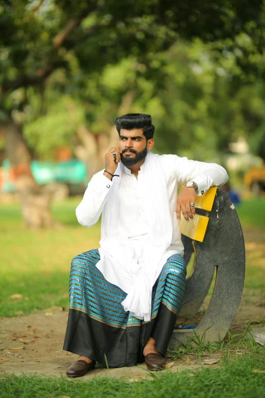 a man sitting on a bench talking on a cell phone, an album cover, by Max Dauthendey, pexels contest winner, kerala village, pose model, dressed thobe, an angry