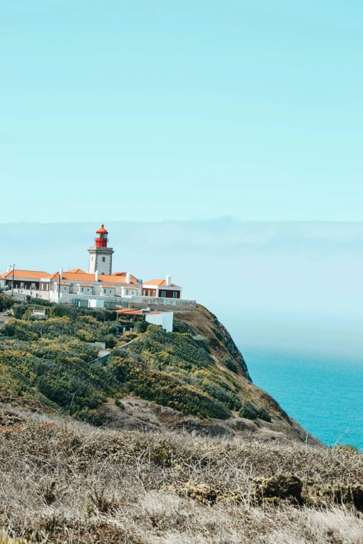 a lighthouse sitting on top of a hill next to the ocean, square, portugal, slide show, multiple stories