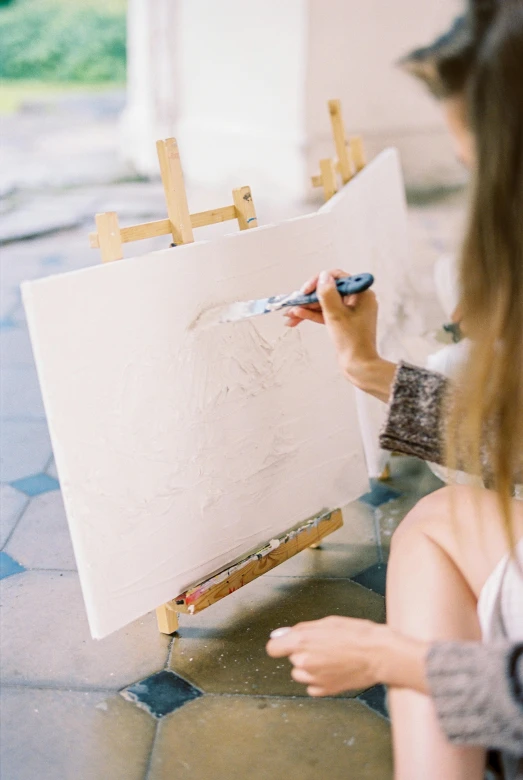 a woman is painting a picture on an easel, pexels contest winner, arbeitsrat für kunst, white paint, chalk texture on canvas, symmetrical painting, on a white table