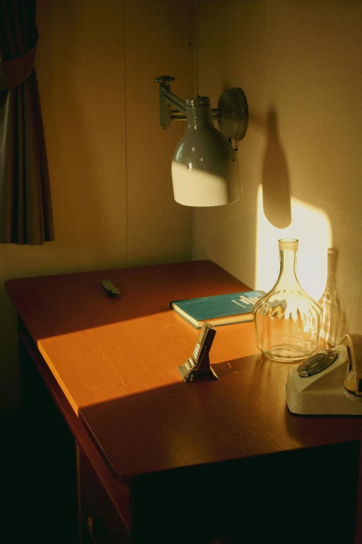 a desk with a lamp and a book on it, a still life, inspired by Nan Goldin, flickr, light and space, sun shafts, 1999 photograph, studio ghibli sunlight, ( ( photograph ) )