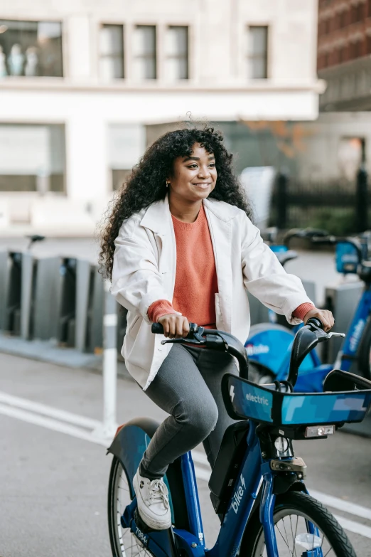 a woman riding a bike on a city street, trending on pexels, happening, blue accents, black. airports, smiling, avatar image