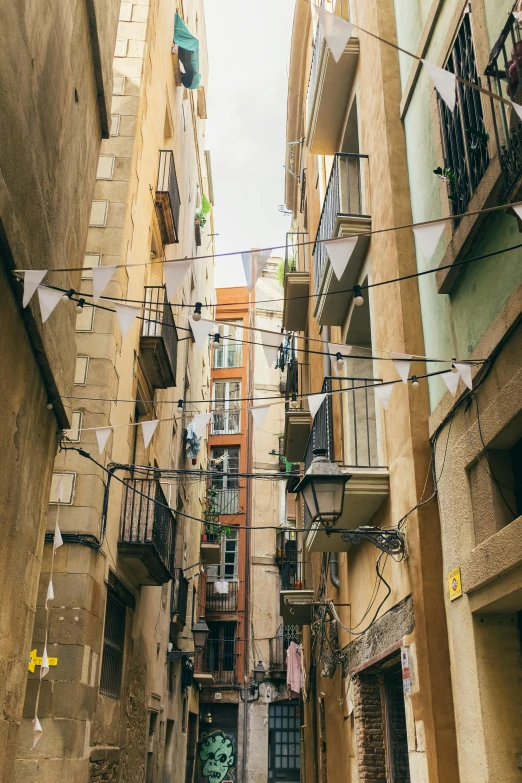 a couple of people walking down a narrow street, inspired by Modest Urgell, unsplash, conceptual art, hanging cables, balconies, decorations, sparsely populated