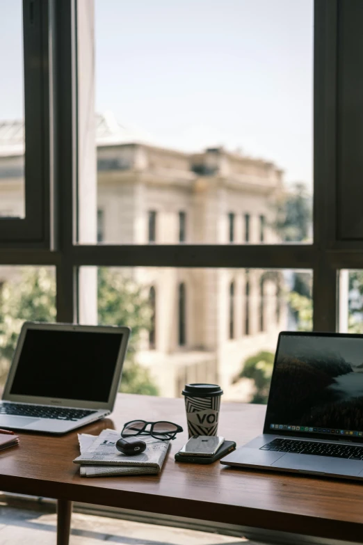 a couple of laptops sitting on top of a wooden desk, trending on pexels, modernism, large open windows, library of congress, city morning, glass ceilings