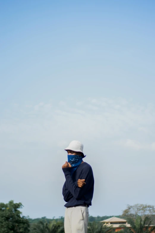 a man standing on top of a lush green field, a picture, unsplash, dust mask, shades of blue and grey, standing on rooftop, ((blue))