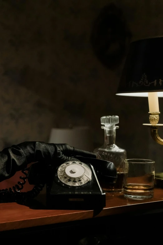 a telephone sitting on top of a wooden table next to a lamp, a still life, inspired by Elsa Bleda, romanticism, jack the ripper, absinthe, gloves and jewelry. motion, 2030s