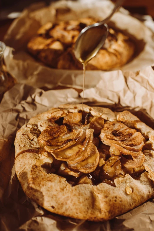 a couple of pizzas sitting on top of a table, a still life, pexels contest winner, renaissance, apple pie, dripping honey, brown paper, organic detail