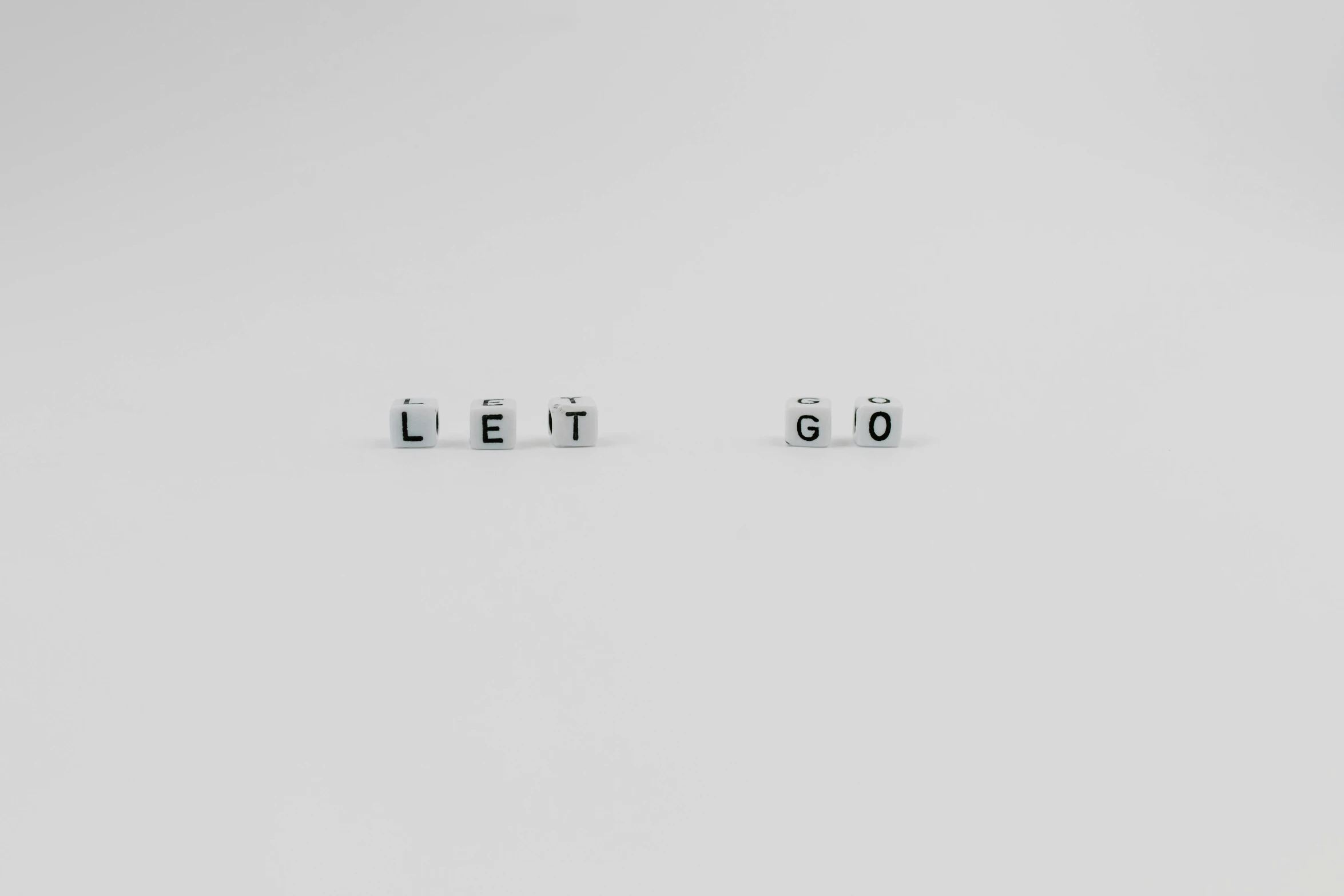 a couple of dice pieces sitting on top of each other, by Emma Andijewska, minimalism, of letting go, word, lost series, letters