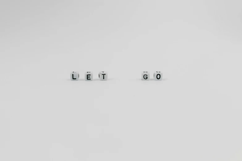 a couple of dice pieces sitting on top of each other, by Emma Andijewska, minimalism, of letting go, word, lost series, letters