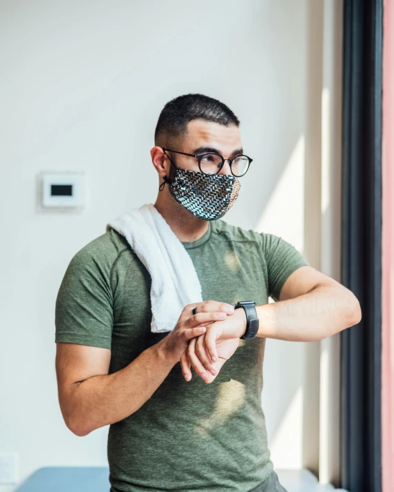 a man standing in front of a window wearing a face mask, a colorized photo, trending on pexels, happening, wearing a watch, wearing tanktop, non-binary, wearing military outfit