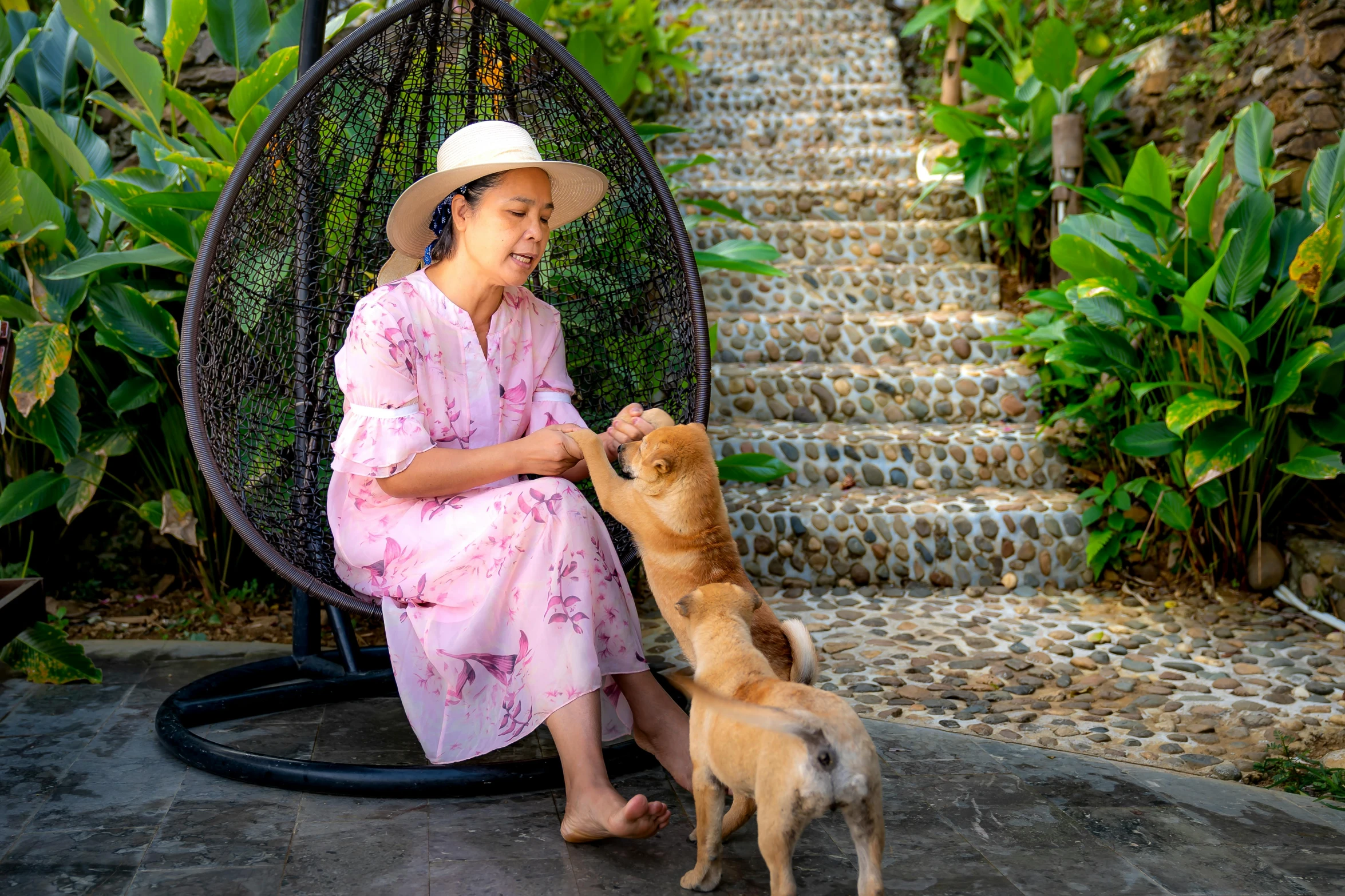 a woman sitting in a chair petting a dog, pexels contest winner, in style of thawan duchanee, in the garden, avatar image, resort