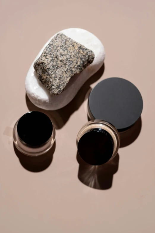 a couple of items sitting on top of a table, dark eyeliner, smooth rocks, skin care, solarised