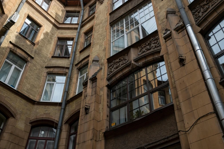 a tall brick building with lots of windows, a photo, by Konrad Witz, pexels contest winner, art nouveau, post - soviet courtyard, фото девушка курит, brown, looking around a corner