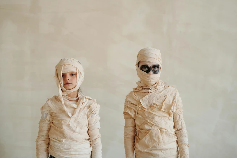 two people dressed as mummys standing next to each other, by Ellen Gallagher, pexels contest winner, arte povera, bandages, boys, egyptian, beautiful sci - fi twins