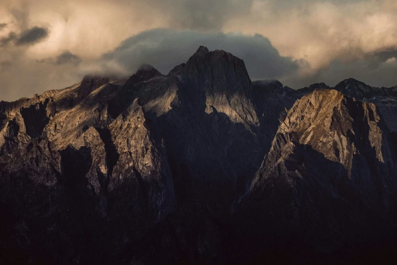 a group of mountains under a cloudy sky, unsplash contest winner, australian tonalism, sharp cliffs, dramatic light 8 k, larapi, filtered evening light