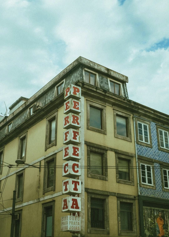 a tall building sitting on the side of a street, an album cover, pexels contest winner, portugal, old signs, {perfect face}, perfect letters