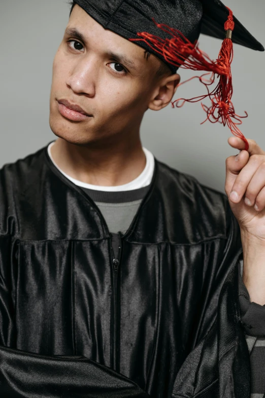 a young man wearing a graduation cap and gown, an album cover, trending on pexels, academic art, featuring brains, roots, leather robes, non binary model