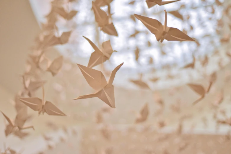 a bunch of origami hanging from a ceiling, inspired by Ai Weiwei, trending on unsplash, visual art, doves flying into the portal, cream paper, 2000s photo, holly herndon origami statue